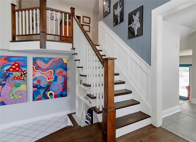 stairs featuring tile patterned floors and wainscoting