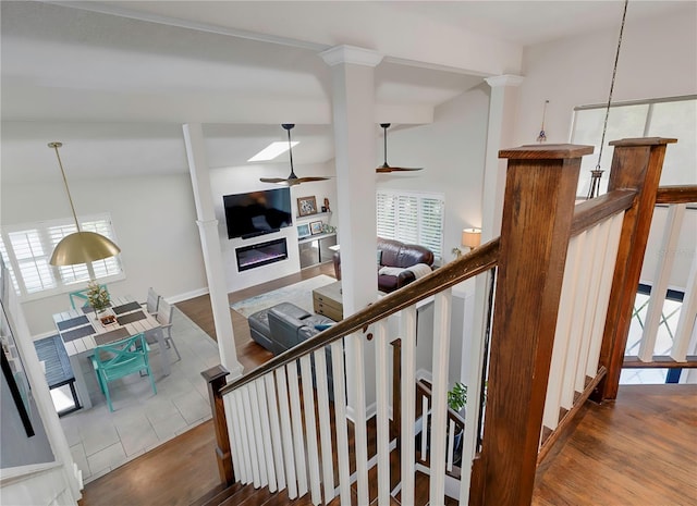 stairway with ceiling fan, a glass covered fireplace, and wood finished floors