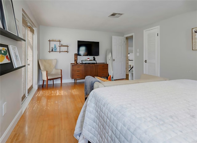 bedroom featuring baseboards, light wood-style floors, and visible vents