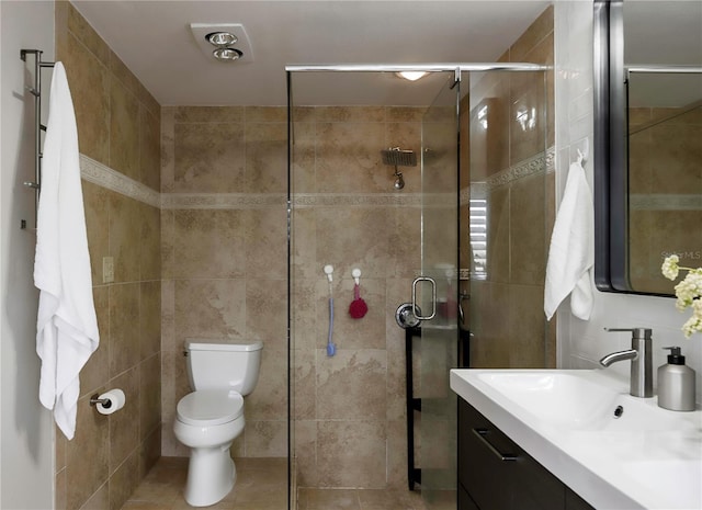 bathroom with a stall shower, tile walls, vanity, and toilet