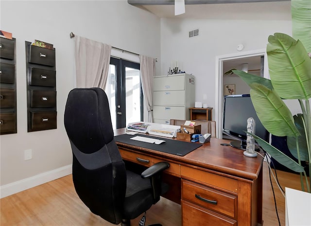 office space with light wood finished floors, visible vents, baseboards, and high vaulted ceiling