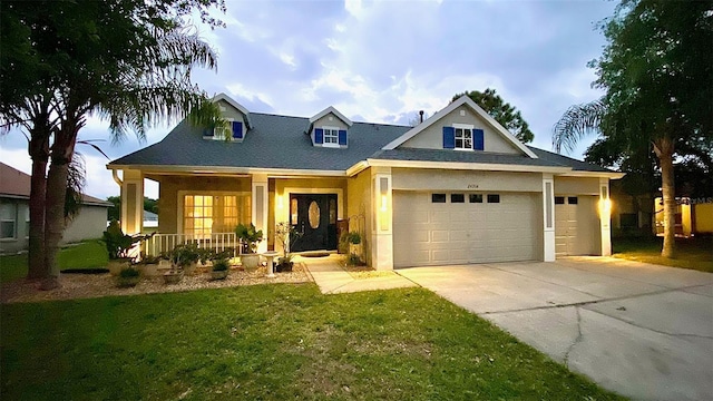 view of front facade with driveway, covered porch, a front yard, stucco siding, and a garage