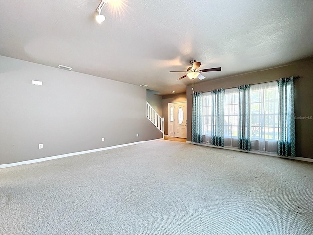 spare room featuring ceiling fan, stairs, visible vents, baseboards, and carpet floors