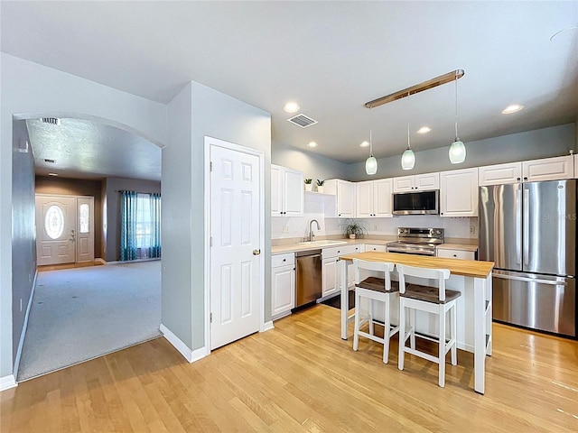 kitchen featuring a sink, visible vents, arched walkways, white cabinets, and appliances with stainless steel finishes