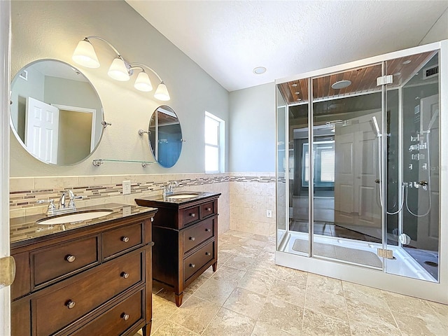 bathroom featuring tile walls, a sink, wainscoting, and two vanities