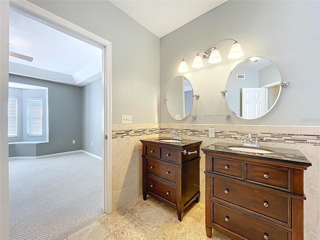 bathroom featuring tile walls, a sink, tile patterned floors, and two vanities