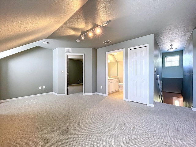 additional living space with visible vents, light carpet, and a textured ceiling