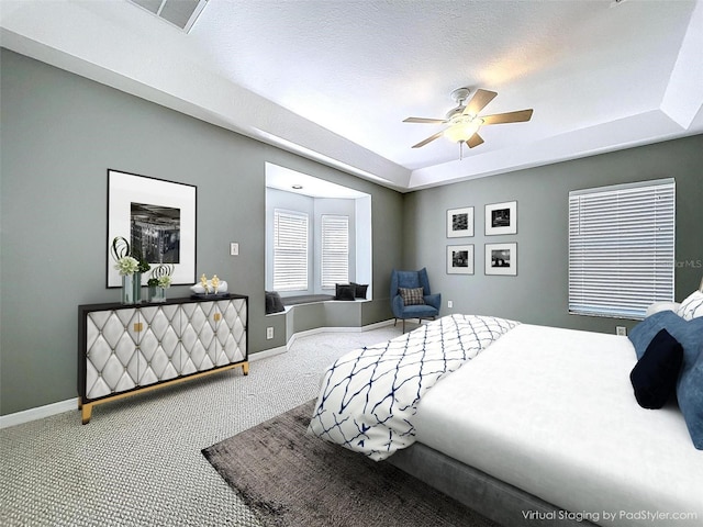 bedroom featuring ceiling fan, a tray ceiling, visible vents, baseboards, and carpet floors