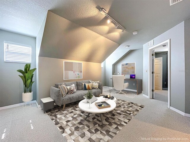 carpeted living area featuring a textured ceiling, visible vents, baseboards, vaulted ceiling, and rail lighting