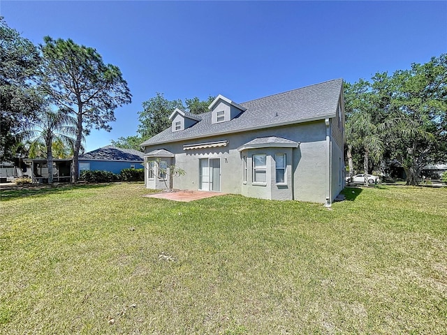 back of property featuring stucco siding, roof with shingles, and a yard