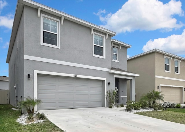 traditional home featuring an attached garage, driveway, and stucco siding