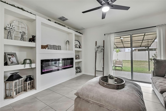 living room featuring a glass covered fireplace, built in features, tile patterned flooring, a ceiling fan, and visible vents
