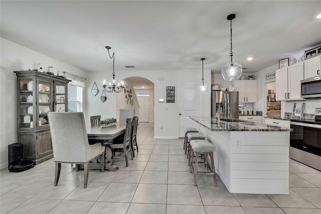 dining space featuring baseboards, a chandelier, light tile patterned flooring, visible vents, and arched walkways
