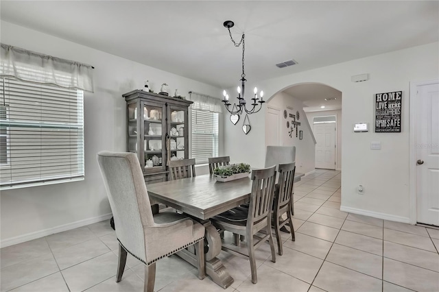 dining space featuring visible vents, arched walkways, a notable chandelier, and light tile patterned flooring