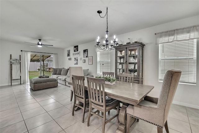 dining room with ceiling fan with notable chandelier, light tile patterned flooring, and baseboards