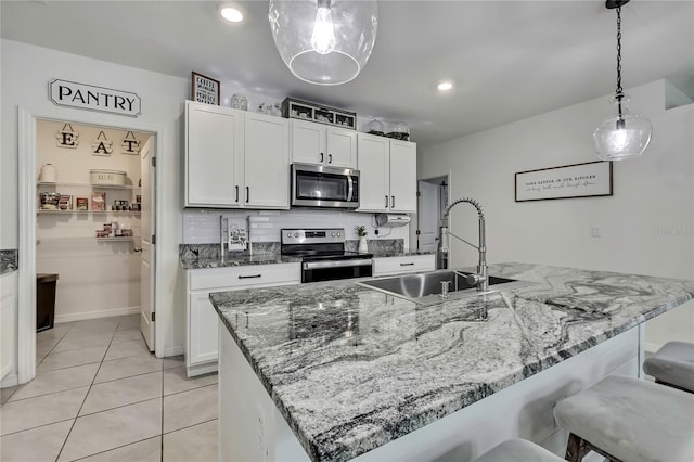 kitchen with a kitchen breakfast bar, white cabinetry, light tile patterned flooring, a sink, and stainless steel appliances