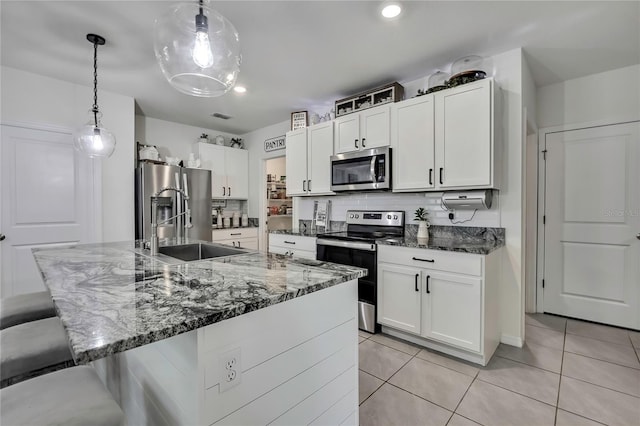 kitchen with a breakfast bar, light tile patterned flooring, decorative backsplash, stainless steel appliances, and a sink