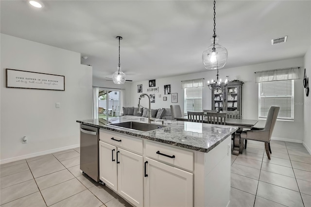 kitchen featuring visible vents, light tile patterned floors, dishwasher, a sink, and dark stone counters