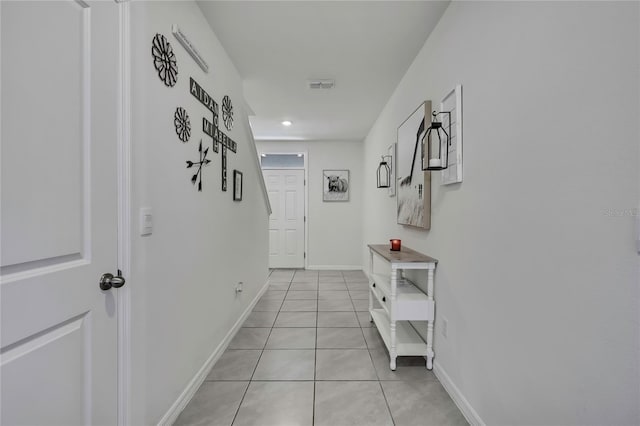 corridor with visible vents, baseboards, and light tile patterned flooring