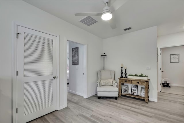 sitting room featuring visible vents, ceiling fan, light wood finished floors, and baseboards