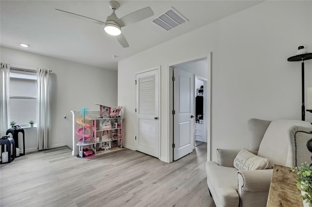 living area featuring light wood-style floors, baseboards, a ceiling fan, and visible vents