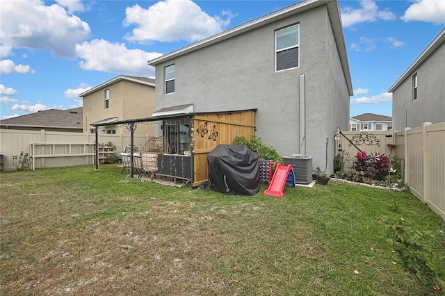 back of property featuring central AC unit, a fenced backyard, a lawn, and stucco siding