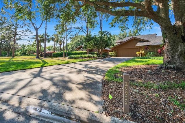 view of front of home featuring concrete driveway, a front lawn, stucco siding, and an attached garage