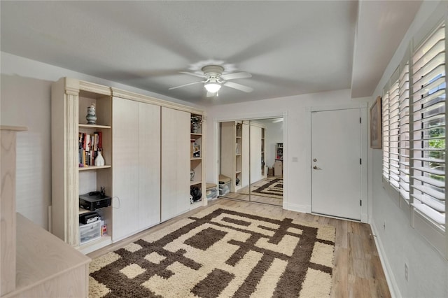 entryway with baseboards, a ceiling fan, and light wood finished floors
