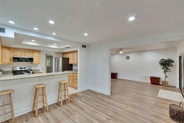 kitchen featuring light wood-style flooring, visible vents, a raised ceiling, stainless steel appliances, and light brown cabinetry