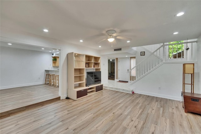 unfurnished living room with baseboards, recessed lighting, a ceiling fan, stairs, and wood finished floors