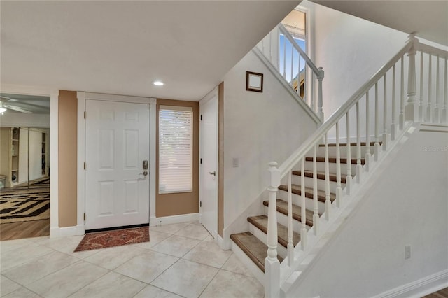 entryway featuring light tile patterned floors, baseboards, a ceiling fan, and stairway