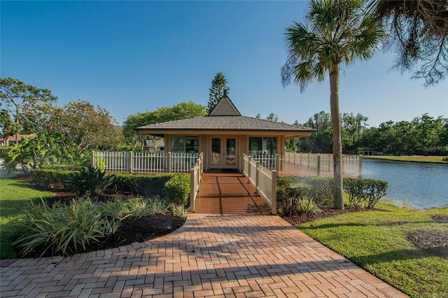 view of front of house with a water view, french doors, and fence