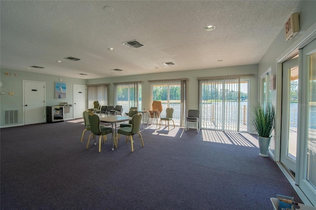 carpeted dining room featuring a textured ceiling and visible vents