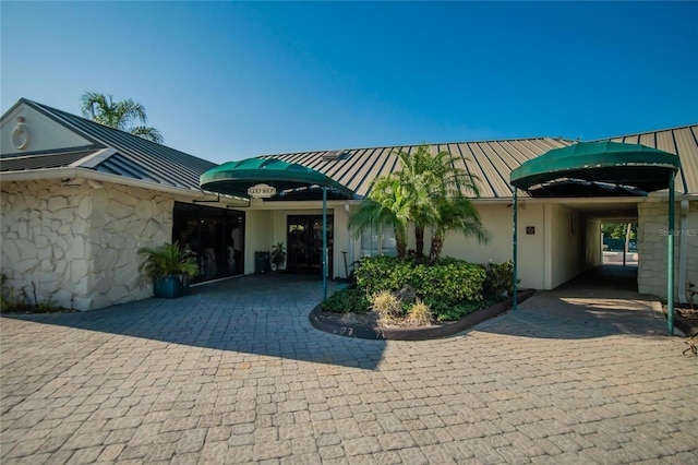 view of front of property with stone siding, metal roof, a standing seam roof, and stucco siding