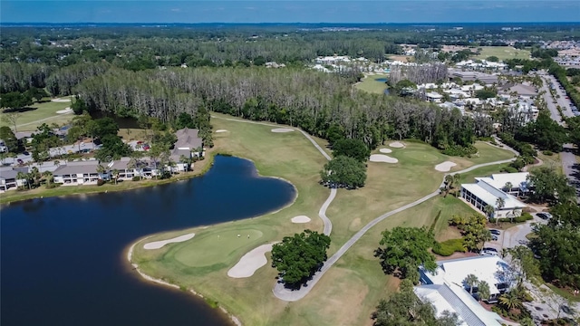 drone / aerial view with a water view, golf course view, and a wooded view