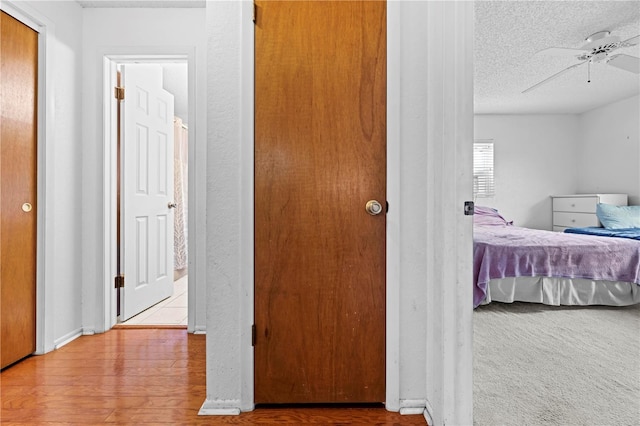 hallway with a textured ceiling and wood finished floors