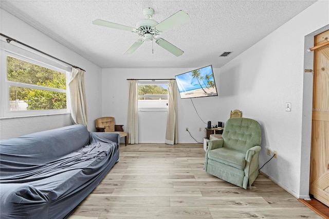 sitting room featuring a ceiling fan, a textured ceiling, visible vents, and light wood finished floors
