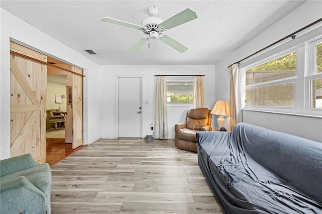 living area with light wood-type flooring, a textured ceiling, and visible vents