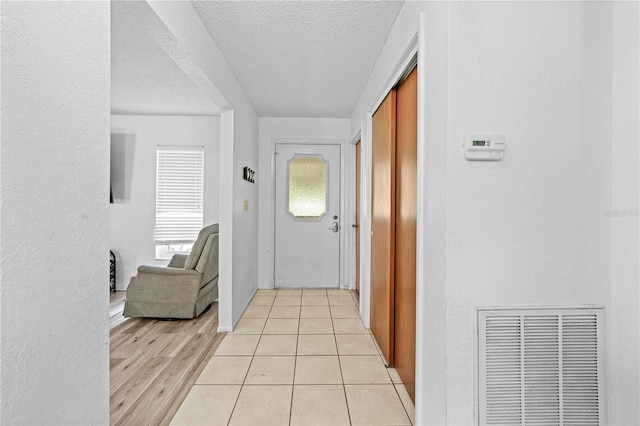 corridor with visible vents, a textured ceiling, and a textured wall