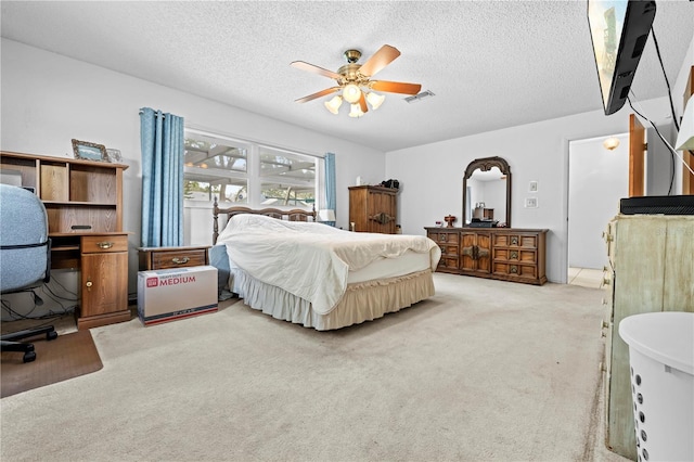 bedroom with a ceiling fan, a textured ceiling, and light carpet