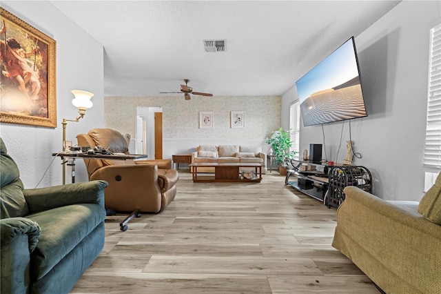 living room with visible vents, light wood finished floors, and ceiling fan