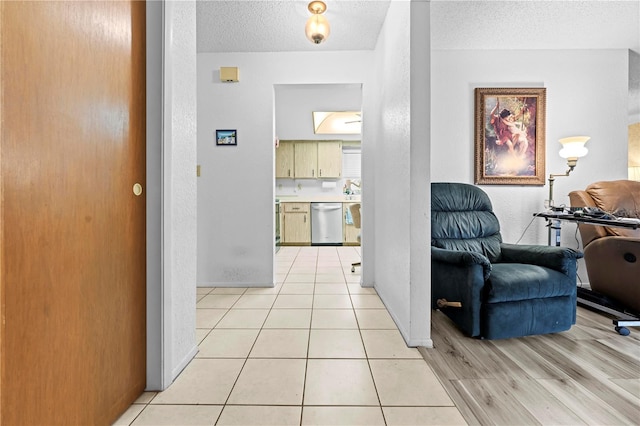 hallway with baseboards, light wood-style flooring, and a textured ceiling