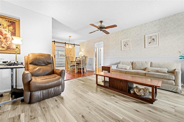 living area with a textured ceiling, ceiling fan, and wood finished floors