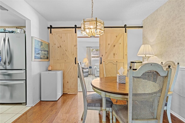 dining area with visible vents, a barn door, light wood-style flooring, and a chandelier