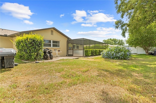 rear view of property with a lanai, a patio area, fence, a yard, and stucco siding