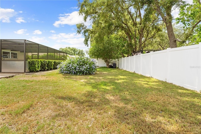 view of yard with a fenced backyard and glass enclosure