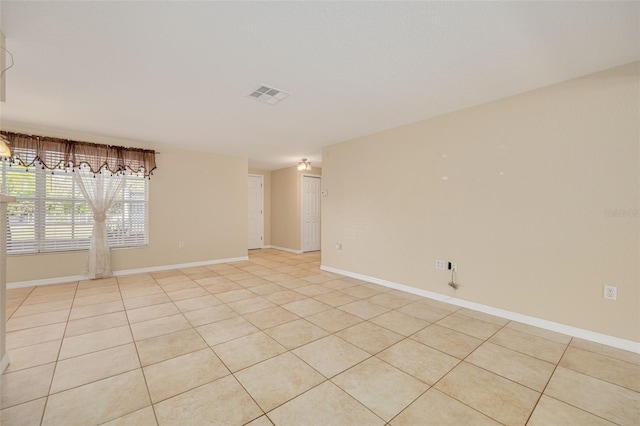 spare room with light tile patterned floors, visible vents, and baseboards