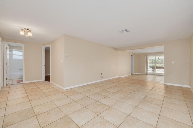 empty room with light tile patterned floors, baseboards, and visible vents