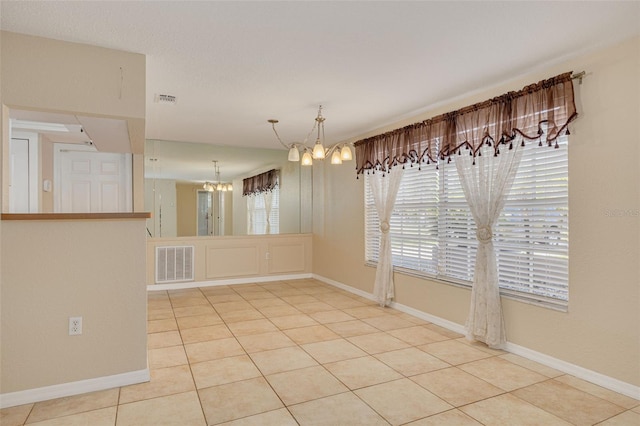 unfurnished dining area featuring a notable chandelier, light tile patterned floors, visible vents, and baseboards