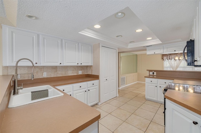 kitchen featuring white cabinetry, visible vents, range with electric cooktop, a raised ceiling, and a sink